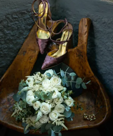 Ramo de flores y zapatos sobre una banqueta de madera