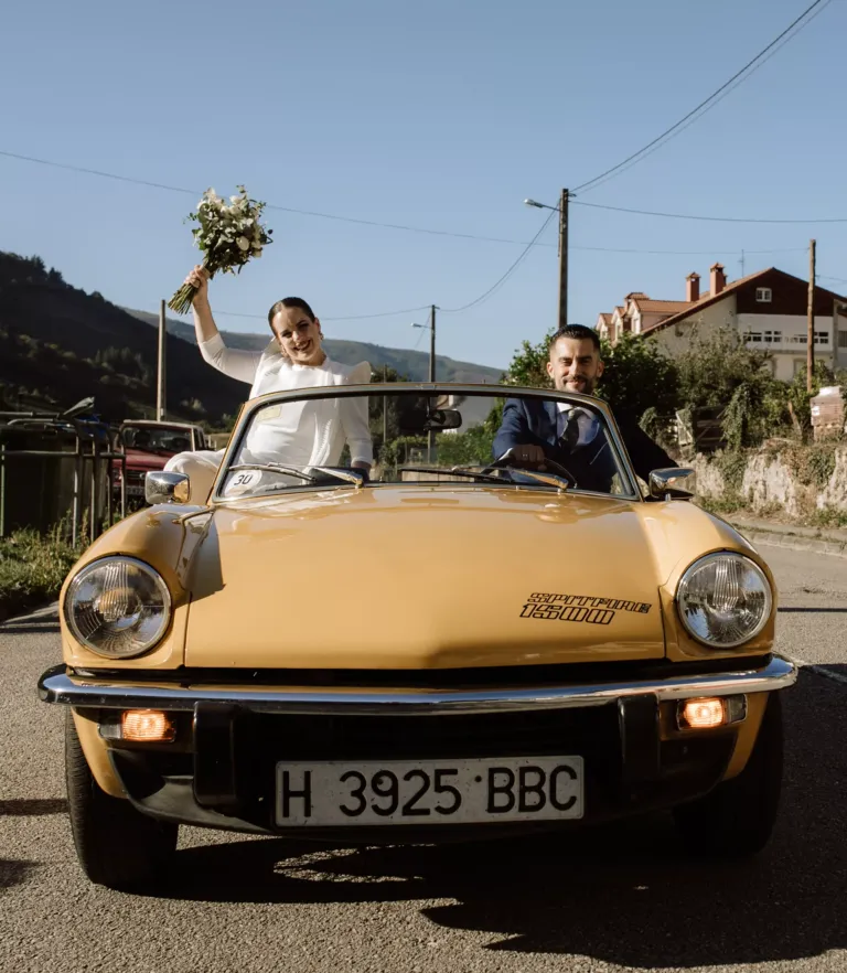 Novia y novio en un descapotable amarillo