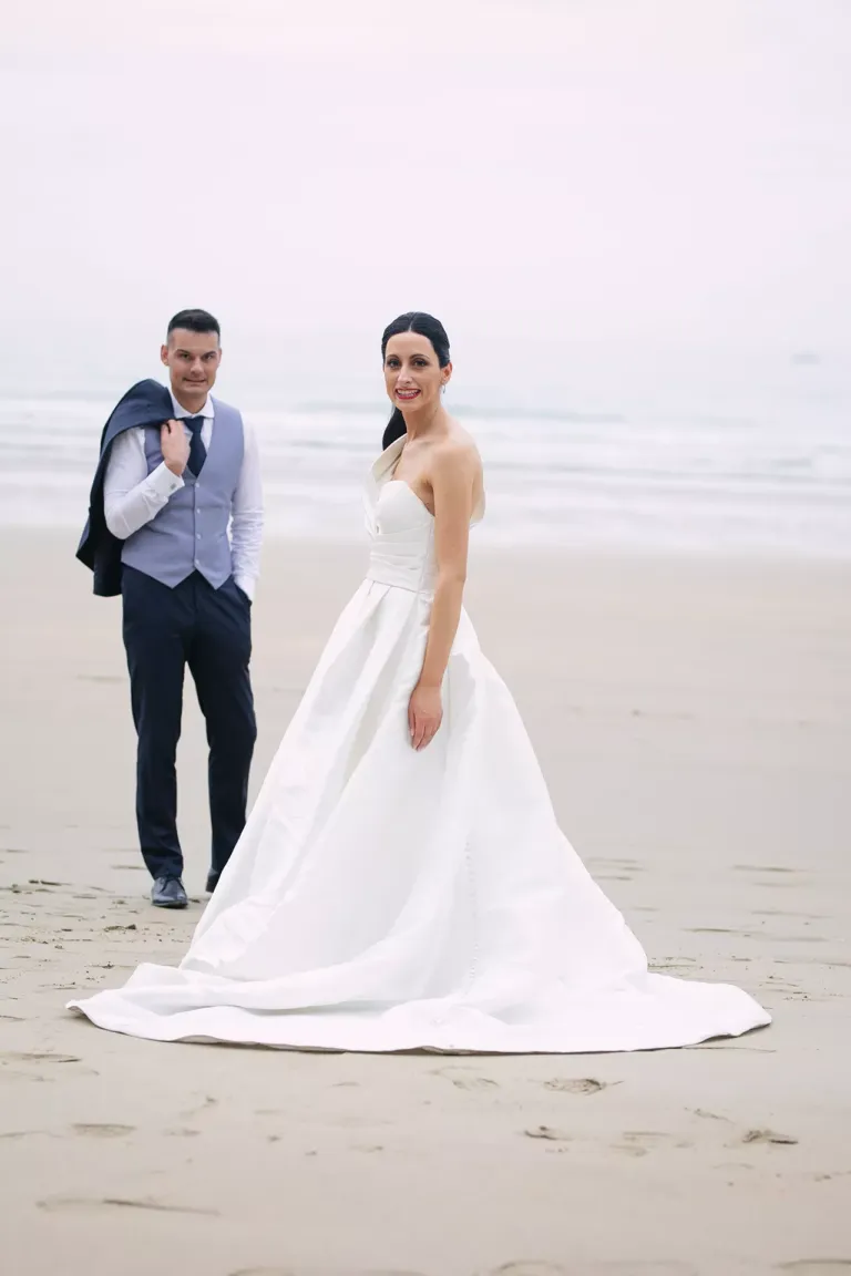 Pareja de novios vestidos de ceremonia en la playa