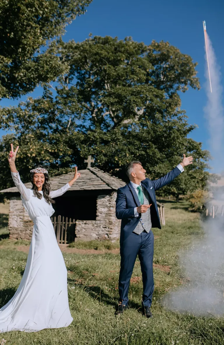 Pareja de novios delante de una capilla tirando un volador