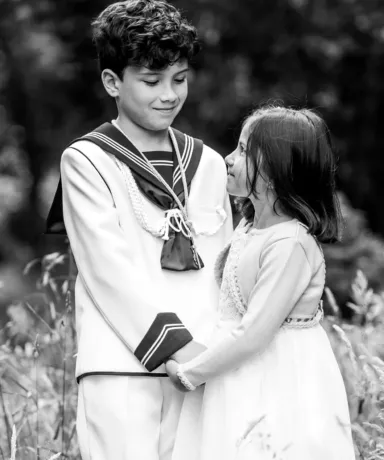 Niño vestido de comunión cogiendo de las manoa una niña más pequeña