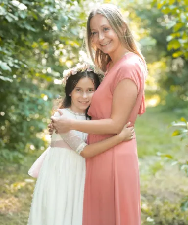 Mujer abrazando a una niña vestida con traje de comunión